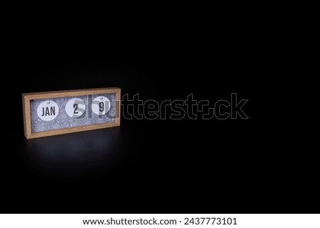 A wooden calendar block showing the date January 29th on a dark black background, save the date or date of event concept