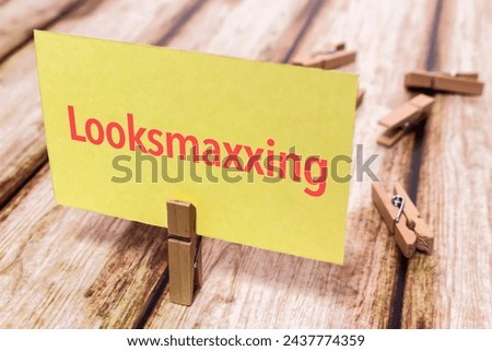 Conceptual message card showing looksmaxxing on shabby wooden table. Nice wooden clothespin or natural wooden pinch holding yellow paper note.
