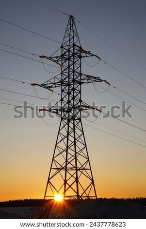 Landscape photograph of a sunset over a field and an electrical high-voltage tower