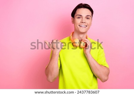 Photo portrait of pretty teenager guy headphones point empty space wear trendy yellow outfit isolated on pink color background