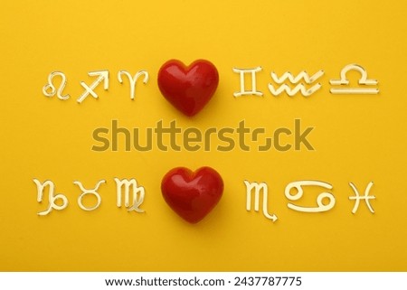 Zodiac compatibility. Signs with red hearts on yellow background, flat lay Royalty-Free Stock Photo #2437787775