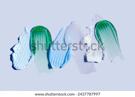 Cosmetic products green, blue, white texture smudge  assortment on blue background 