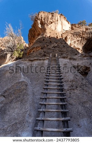 Wood ladder to Alcove House in Bandelier National Monument. Ancestral Puebloan home in New Mexico. Long log ladder up cliff face to reach the lofty home above the Frijoles Canyon. Royalty-Free Stock Photo #2437793805
