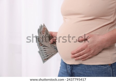 Surrogate mother. Pregnant woman with dollar banknotes indoors, closeup. Space for text