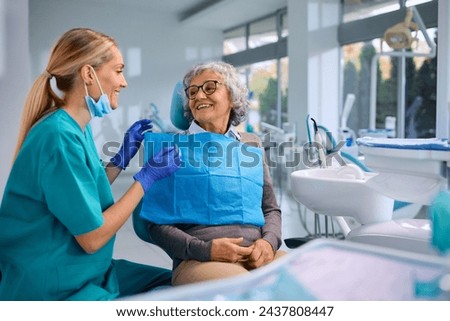 Happy elderly woman talking to her orthodontist during appointment at dentist's office. Royalty-Free Stock Photo #2437808447