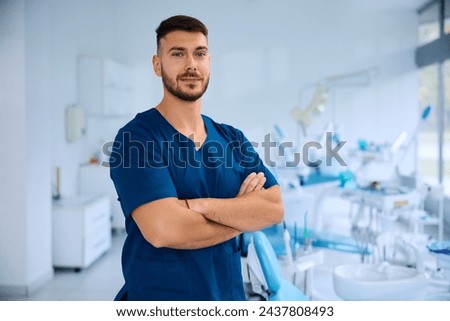 Confident dentist with arms crossed at dental clinic looking at camera. Copy space.  Royalty-Free Stock Photo #2437808493