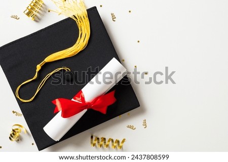 Graduation party concept. Flat lay square academic cap with diploma and gold tinsel on white background. Royalty-Free Stock Photo #2437808599
