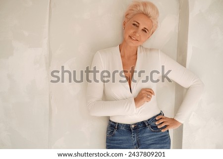 Portrait of a blonde, short hairstyle woman looking at the camera with gentle smile. Mature woman feeling calm and happy. Real people. Copy space.