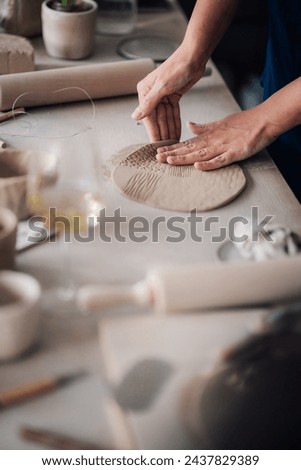 Cropped picture of pottery course mentor showing students wet clay shaping and contemporary earthenware making in modern workshop. Close up of tutor's hands shaping wet flatten clay on pottery class.