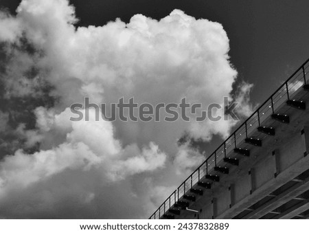 black and white picture of the side view of a bridge for a railway track against the backdrop of cloudy skies