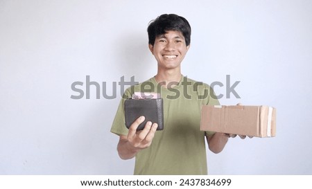 smiling asian man holding money package and wallet on isolated white background