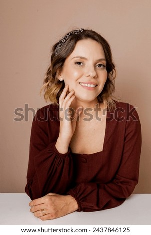 Young woman smiling, with brown hair and brown blouse on isolate