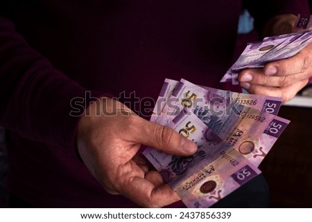 Male hands counting Mexican money, paying with Mexican bills. Royalty-Free Stock Photo #2437856339