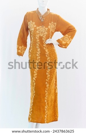 Gold long dress with long sleeves, have a feminine pattern made from soft and cool cotton. Royalty-Free Stock Photo #2437863625