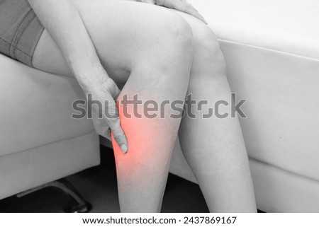 Black and white photo of woman, She shows suffering from leg pain. Medical and health concept.