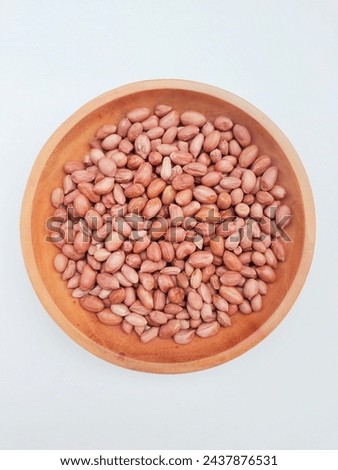 Raw peanuts in a plate on a white background.