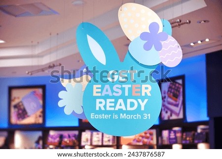Beautiful Get Easter Ready sign against blurred chocolate store background. Easter is March 31 2024 this year.