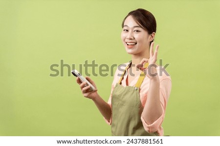Photo of young Asian female housekeeper on green background
