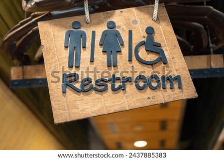 Ceiling wooden restroom or toilet direction sign with gentleman, lady and disability person icon. Sign and symbol object photo.