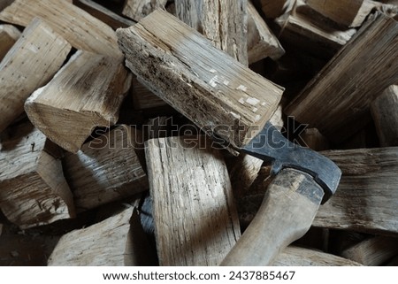 A wood chopping axe lies against the background of oak split firewood