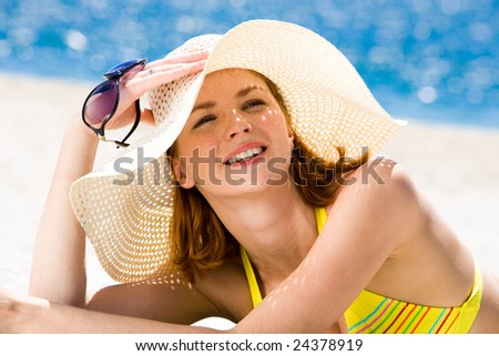 Photo of resting woman in hat holding sunglasses and sunbathing