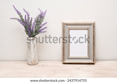 The layout of the frame with a purple bouquet of flowers. A mock-up of an old white portrait frame. Layout of an empty white frame for the design. Royalty-Free Stock Photo #2437914755