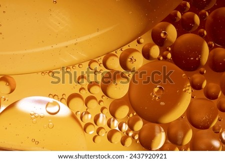 Macro photography. Yellow drops of oil or serum, and beer bubbles texture the background. Oil drops on the water's surface.  Royalty-Free Stock Photo #2437920921