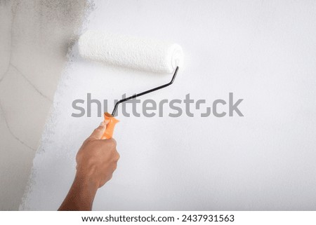 Painter is painting the interior wall white	