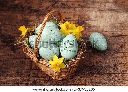 Greeting card Happy Easter: Inscribed Easter egg with Easter eggs and flowers in a basket. Spanish inscription translates as Happy Easter. Royalty-Free Stock Photo #2437935205