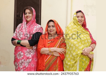 A group of rural Indian hindu women in colorful traditional dresses posing in front of the camera at village. Rural Indian women in at home in village.
