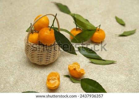 Small oranges fruit or tangarine in rattan basket with brown background. Jeruk Royalty-Free Stock Photo #2437936357