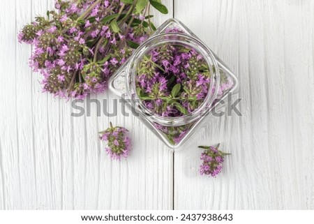 Thymus serpyllum herb in bottle.Thyme is a medicinal herb for dissolving and easier secretion of mucus.Alternative medicine concept on a white wooden table, from above view Royalty-Free Stock Photo #2437938643
