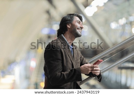View of young man using a smartphone inside a subway - metro station with a blurred view landscape in the background. High quality photo. Texting on the phone. 