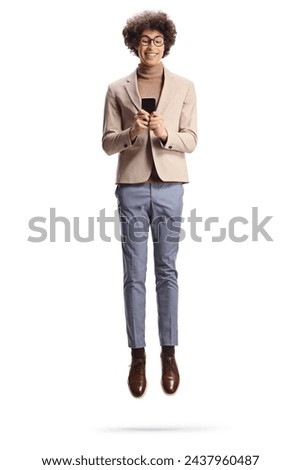 Funny tall guy with glasses using a smartphone and jumping isolated on white background