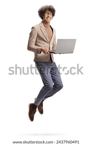 Excited young man holding a laptop computer and jumping isolated on white background