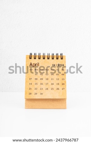 Brown mini desk calendar for April 2024 on white background.