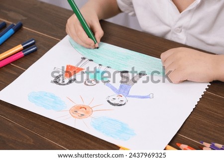 Little boy drawing with pencil at wooden table, closeup. Child`s art
