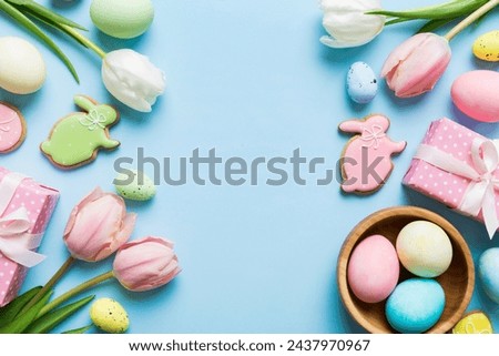 Easter frame with eggs, gift box and tulip on a colored background. The minimal concept. Top view Happy Easter composition. Card with a copy space of the place for the text.