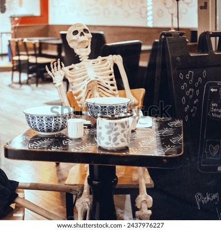 A skeleton is a strange reminder of fate among the everyday as it patiently waits for lunch at a restaurant table.