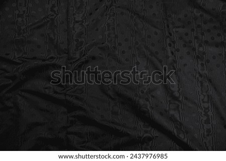 Texture of black taffeta (silk) fabric with black polka-dot pattern, top view. Background, texture of draped dressy fabric with shining black polka-dot pattern. Royalty-Free Stock Photo #2437976985