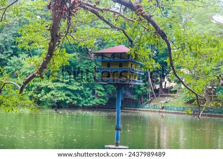 Pigeon cage in the middle of the lake at Gadjah Mada University surrounded by lush trees. Lake park in the city with pigeon house Royalty-Free Stock Photo #2437989489