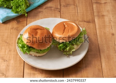 Delicious hamburger with green salad on a wooden table.