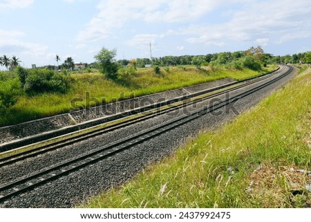 Indonesian curving long rail train in the middle of grass