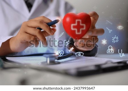 Closeup cardiologist holding red heart shape with virtual medical icons. Health care concept
