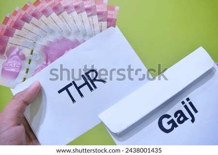 Indonesian Money, rupiah or IDR in envelope with THR Text. The THR envelope contains IDR 100,000 in cash. THR is a holiday allowance on Eid al-Fitr or Eid al-Fitr. best quality green background