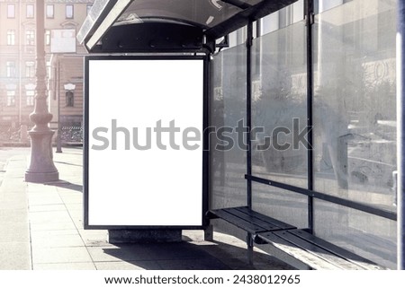 Empty white poster with mockup in lightbox on bus stop in front of urban city street with large glass window and bench.