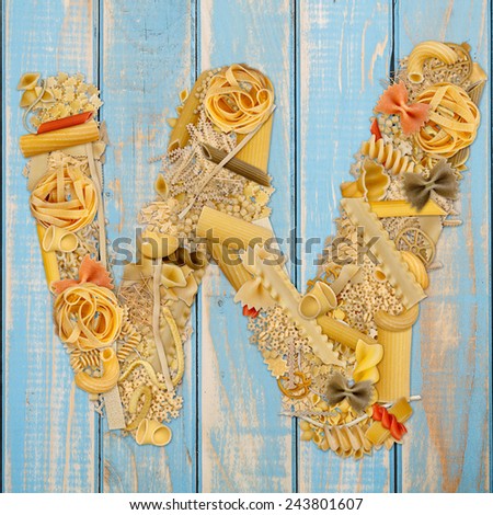 Letter W made from pasta on a blue wooden  background 