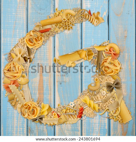 Letter G made from pasta on a blue wooden  background 
