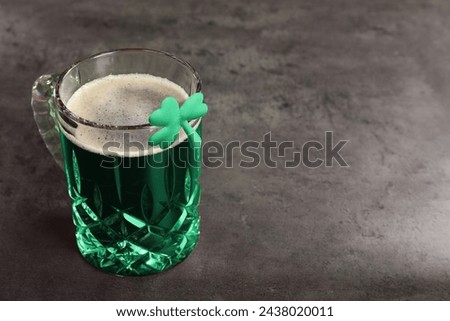 St. Patrick's day celebration. Green beer with decorative clover leaf on grey table. Space for text
