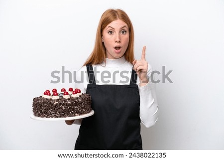 Young redhead woman holding birthday cake isolated on white background intending to realizes the solution while lifting a finger up